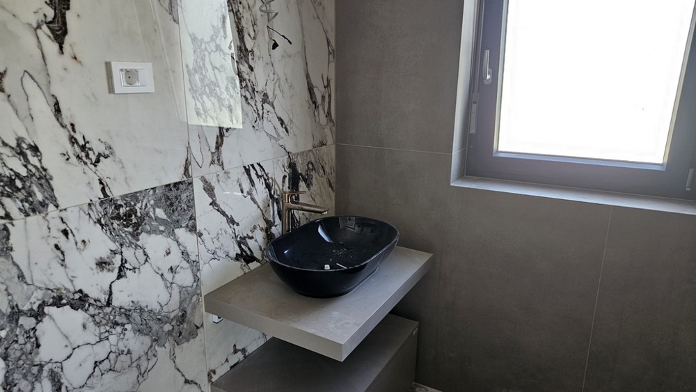 Moderná kúpeľňa s mramorovými doskami na stene.
