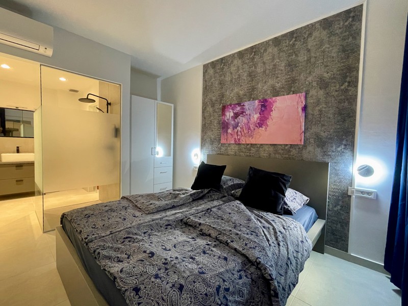 Interiérový pohľad na kúpeľňu so sklenenou sprchovou zástenou a pohľad do svetlej izby v byte na predaj v Zadare, Chorvátsko