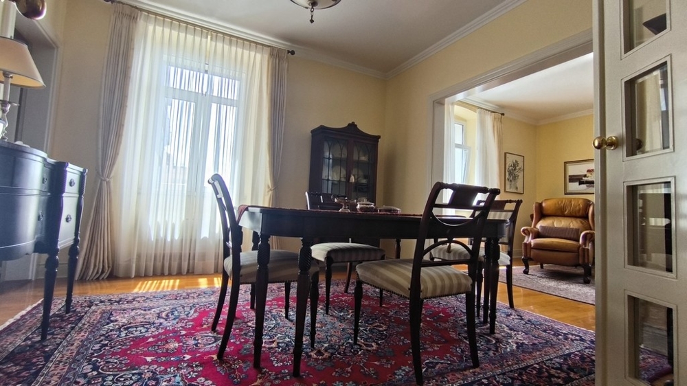 Obývacia časť s jedálenským stolom a kobercom.