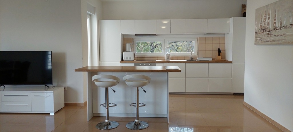 Otvorená kuchyňa s barovými stoličkami vo vysokokvalitnom apartmáne v Opatiji