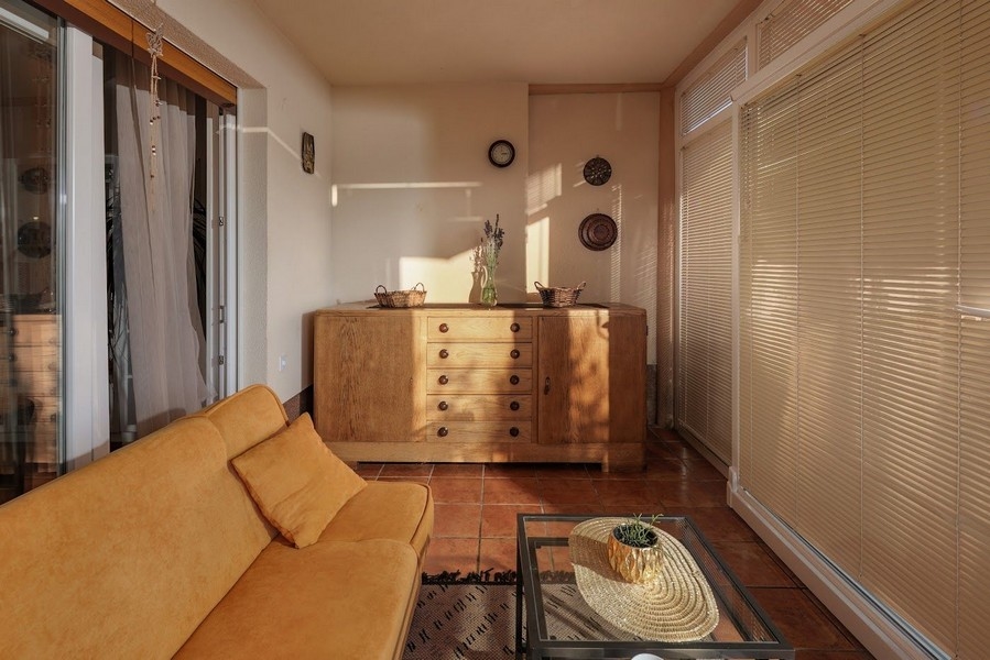 Slnkom zaliata zimná záhrada chorvátskeho bytu so žltou pohovkou.