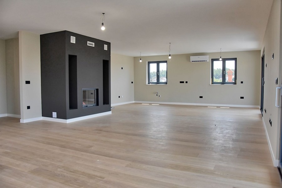 Moderná obývacia izba v strešnom apartmáne na predaj na Istrii s krbom a výhľadom na more.