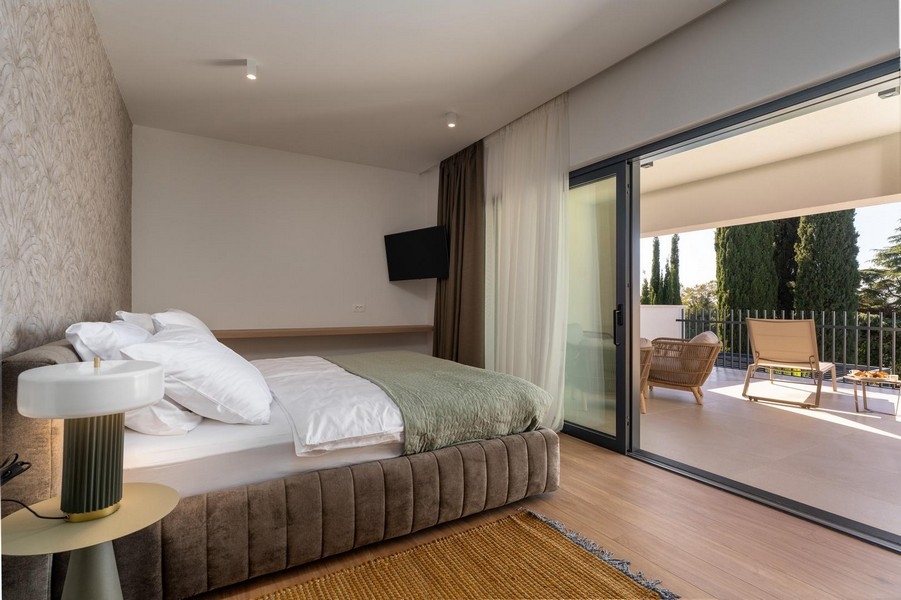 Spálňa s veľkorysým presklením a vstupom na terasu v luxusnom apartmáne na Istrii