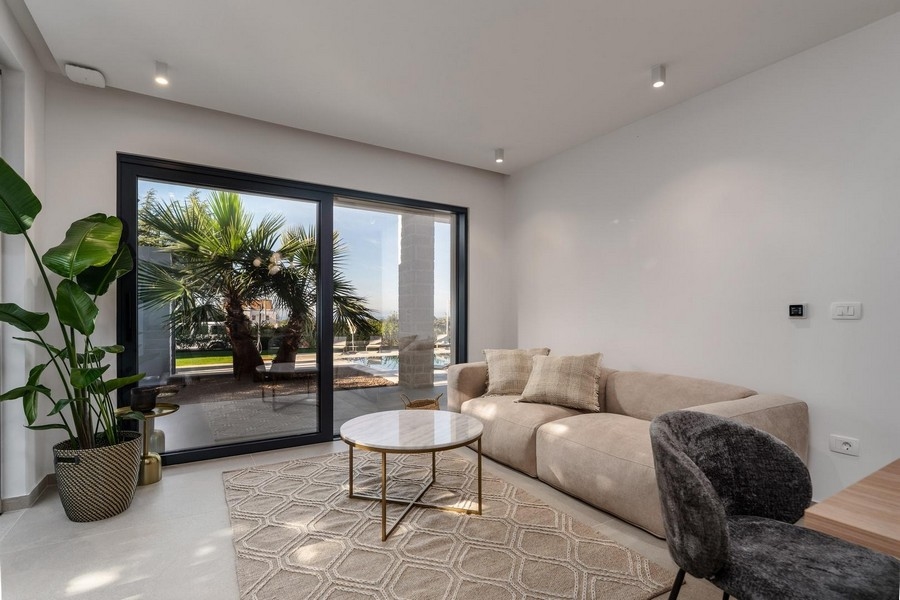 Svetlá obývačka luxusného bytu na Istrii s veľkým oknom do záhrady a štýlovým zariadením