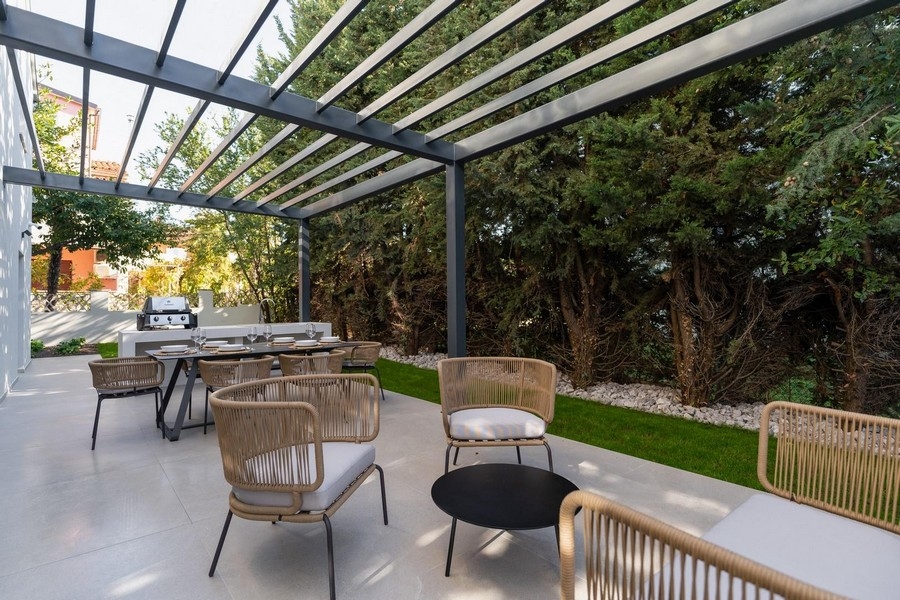 Vonkajší výhľad na terasu s letnou kuchyňou a jedálenským kútom v istrijskom luxusnom apartmáne obklopenom zeleňou