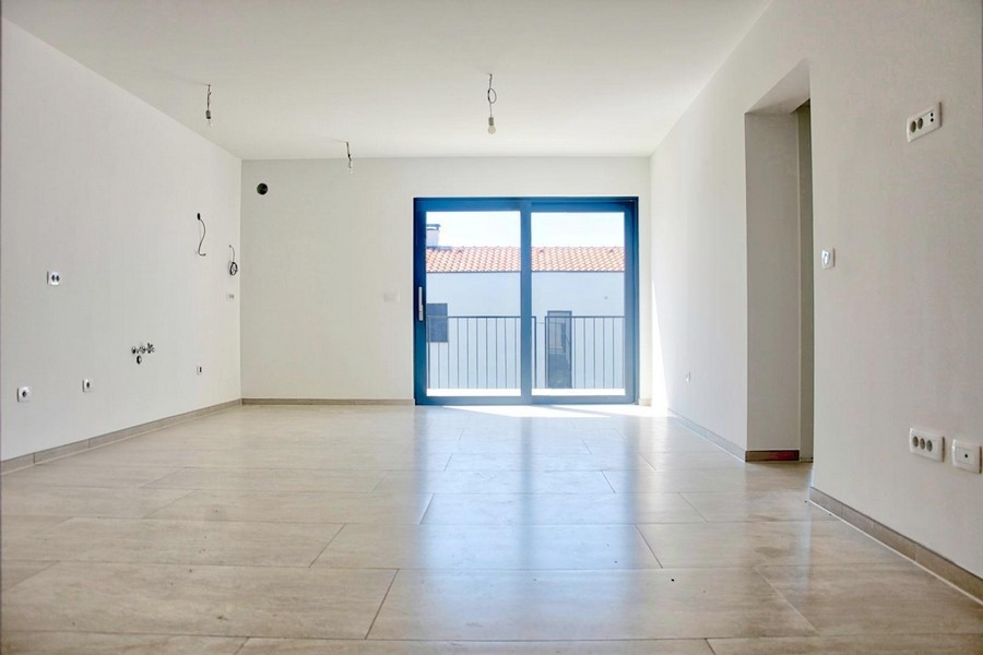 Prázdna svetlá obývačka s veľkými francúzskymi oknami a dlažbou, ponuka realít v Poreči