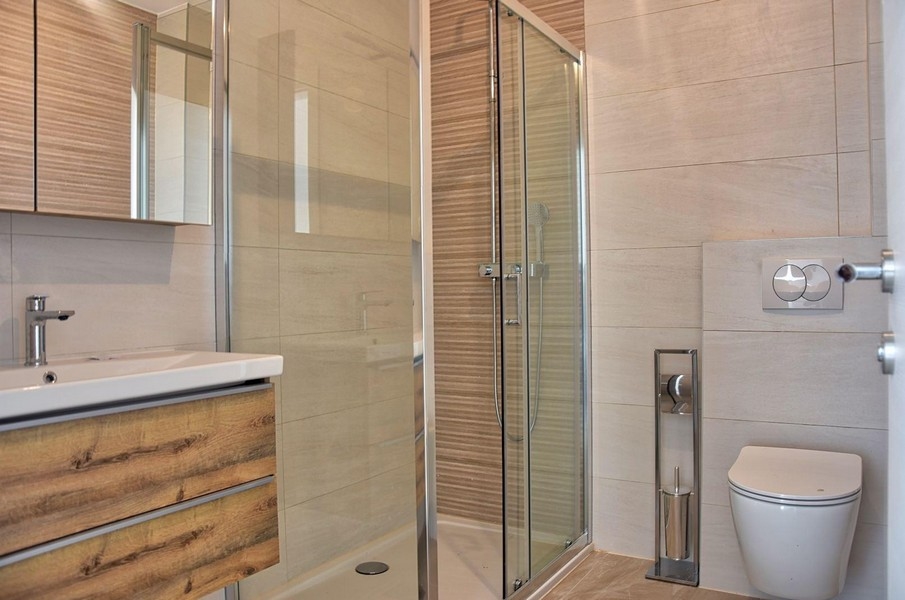 Moderná kúpeľňa so skleneným sprchovacím kútom a drevenými prvkami, nehnuteľnosť v Poreči