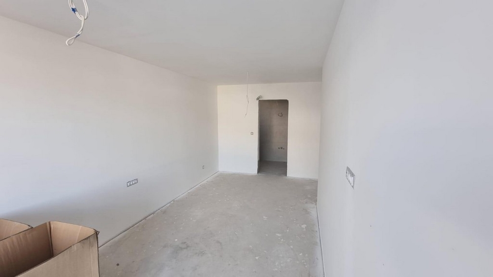 Prázdna miestnosť bytu v Chorvátsku so svetlými stenami a betónovou podlahou.