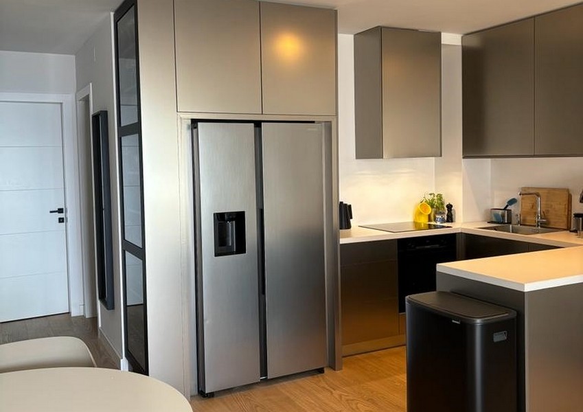 Moderná kuchyňa s chladničkou z nehrdzavejúcej ocele a tmavými skrinkami, súčasť nehnuteľnosti v Rijeke v Chorvátsku.