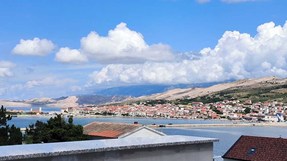 Vonkajší pohľad na parkovaciu plochu bytu na predaj v meste Pag, Chorvátsko, so štrkovým chodníkom