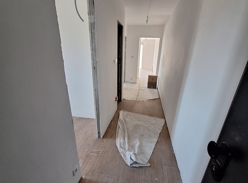 Predsieň v novom byte, ochranný kryt na podlahe, plášť budovy, svetlé steny, drevená podlaha, dvere a izby v pozadí, ponuka od Panorama Skauting v Chorvátsku.