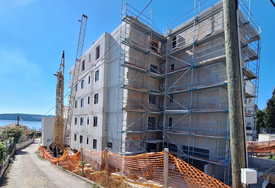 Pohľad zozadu na rozostavaný bytový dom s lešením a žeriavom v Chorvátsku, ponúka Panorama Scouting