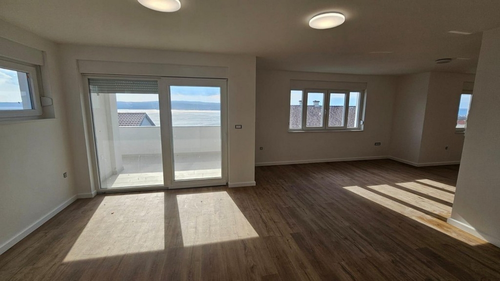 Svetlá obývacia izba s drevenou podlahou bytu na predaj v Crikvenici v Chorvátsku s prístupom na balkón a výhľadom na more