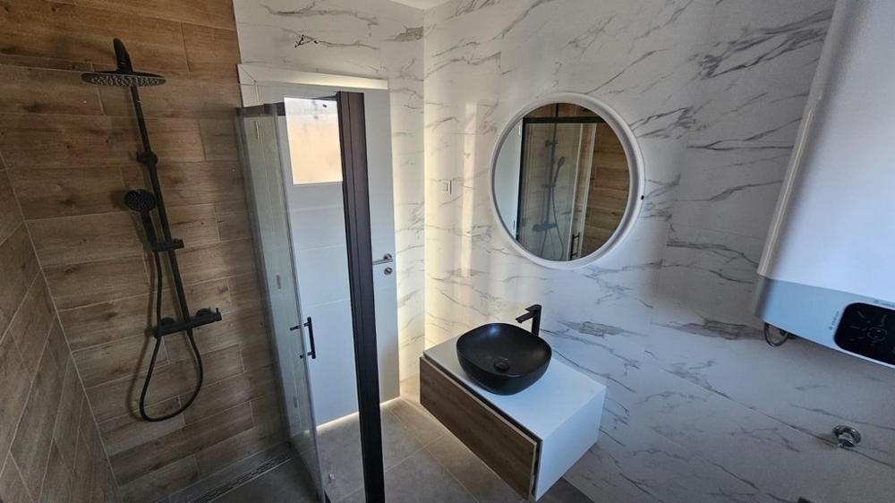 Moderná kúpeľňa v byte na predaj v Crikvenici v Chorvátsku s mramorovými obkladmi, sprchovacím kútom a štýlovým umývadlom