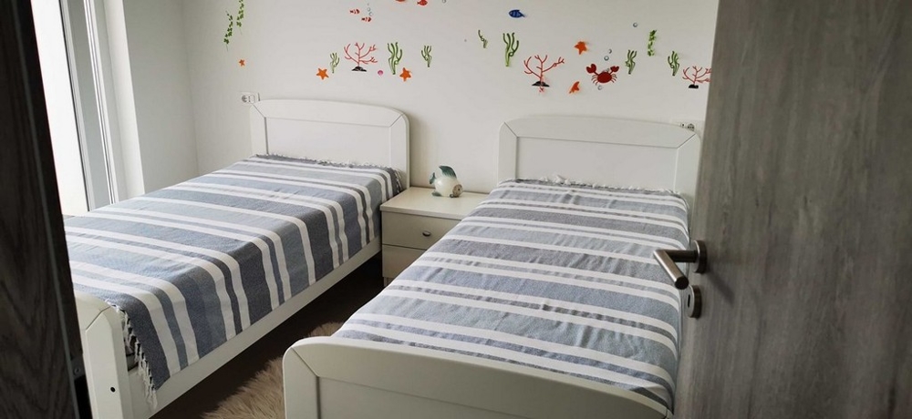Druhá spálňa s dvomi samostatnými lôžkami a veselou dekoráciou na stene, časť bytu na predaj v Tisne, Chorvátsko.