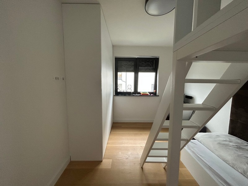 Druhá spálňa s loftovým lôžkom a pracovným priestorom v modernom apartmáne v Rijeke v Chorvátsku.