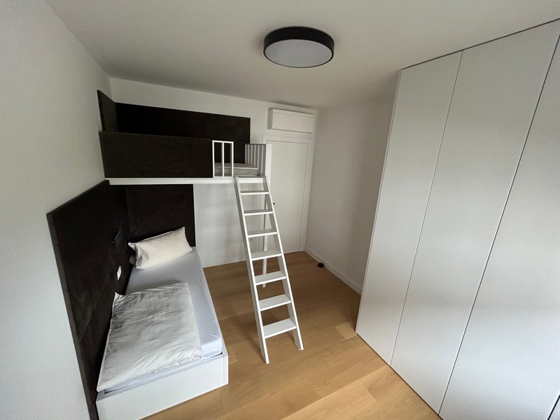 Minimalistická spálňa s loftovou posteľou a rebríkom v modernom apartmáne v Rijeke.