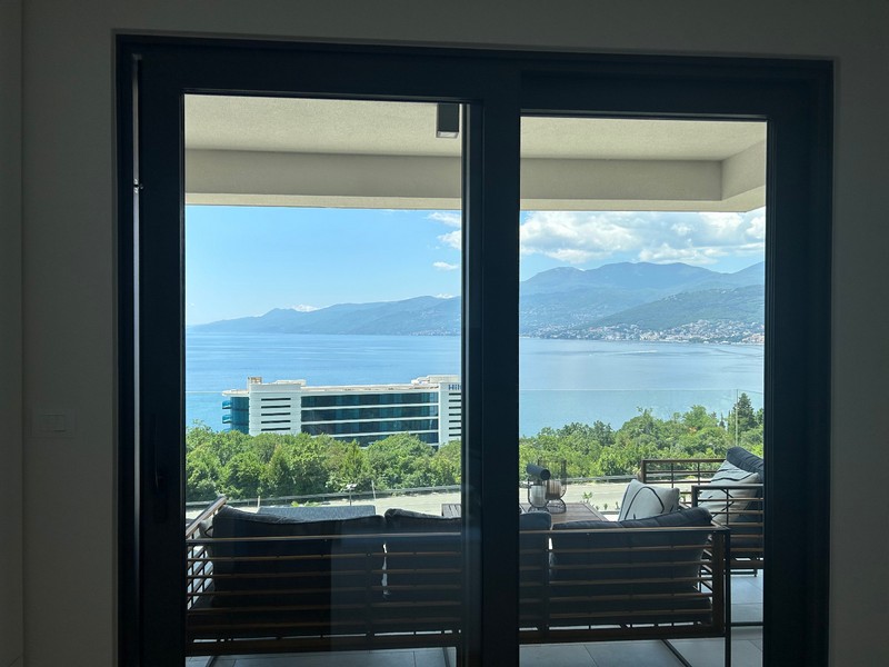 Pohľad cez otvorené patiové dvere moderného apartmánu s výhľadom na Kvarnerský záliv.