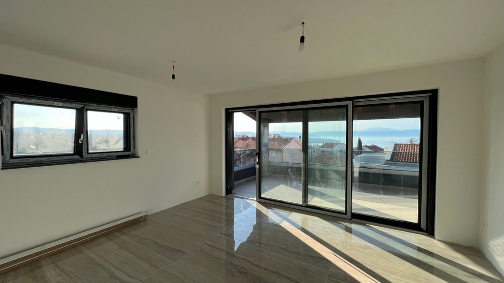 Priestranná obývacia izba s rozsiahlym zasklením a vstupom na terasu, sen pre nehnuteľnosť v Chorvátsku.