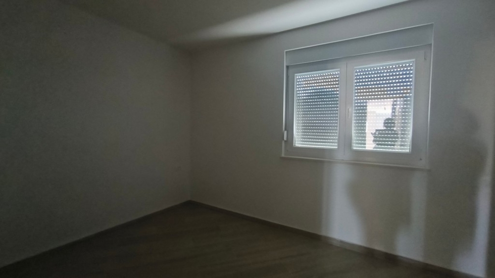 Tmavá miestnosť v novopostavenom penthouse, chorvátska nehnuteľnosť v Šimuni, s oknom a stiahnutými žalúziami.