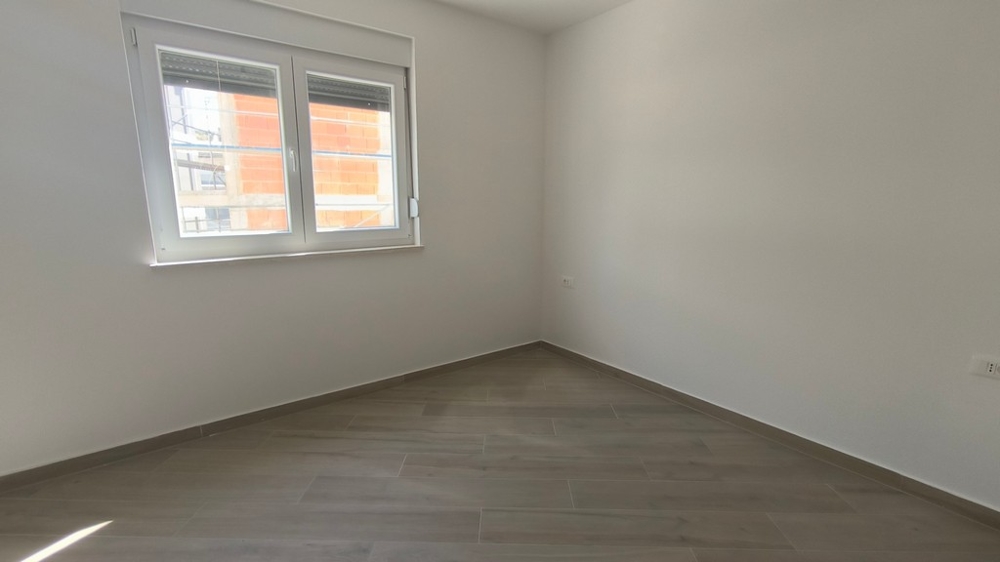 Druhá prázdna spálňa nového strešného apartmánu v Chorvátsku v Šimuni s veľkým oknom.