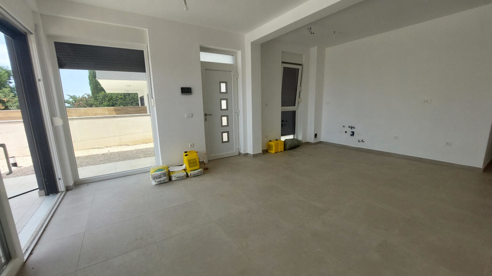 Bočný pohľad na modernú budovu so štrkovým chodníkom a rastlinami pozdĺž steny domu