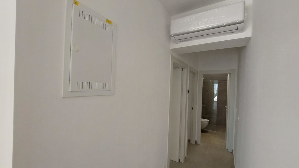 Vnútorný pohľad na prázdnu miestnosť s dláždenou podlahou, veľkými oknami a niekoľkými dverami