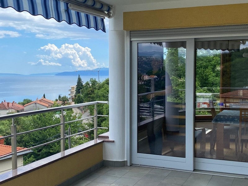 Jedálenský kút s veľkými oknami, ktoré ponúkajú výhľad na more a okolie.