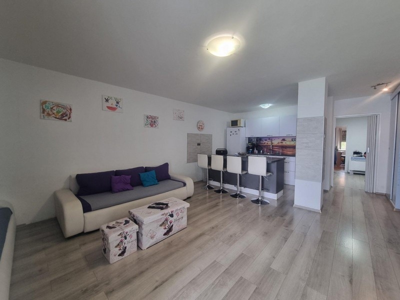 Otvorený obývací priestor s moderným nábytkom a kuchynským kútom v pozadí