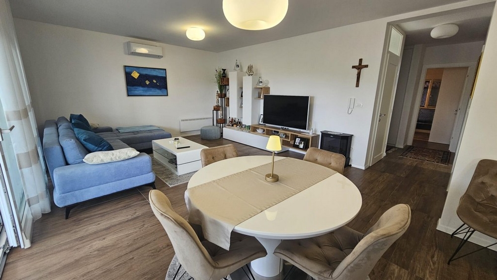 Vysokokvalitná obývacia izba s klimatizáciou, modrým gaučom a modernou smart TV.