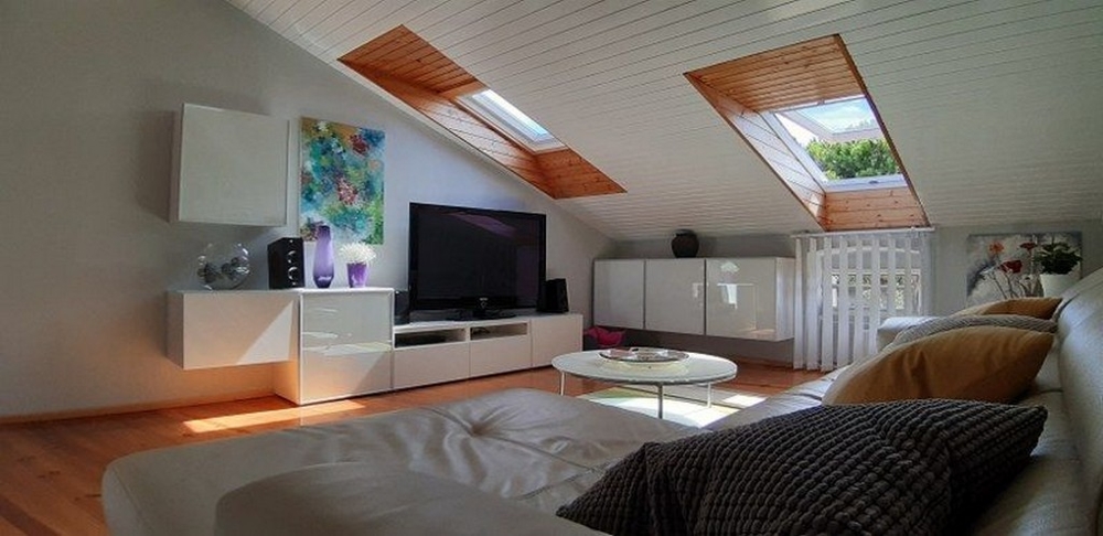 Útulná obývacia izba so strešnými oknami, veľkou televíziou a pohodlnou pohovkou
