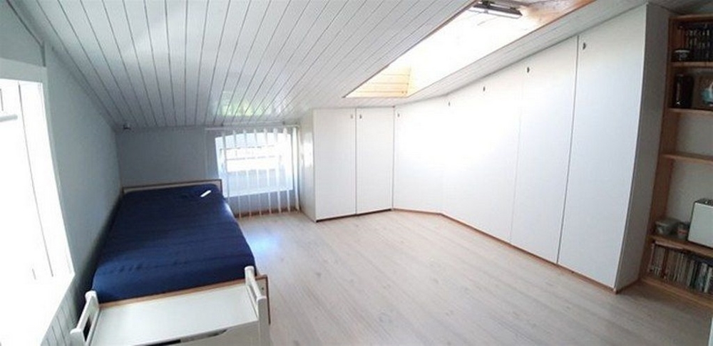 Svetlá, minimalistická spálňa s množstvom úložného priestoru a strešným oknom