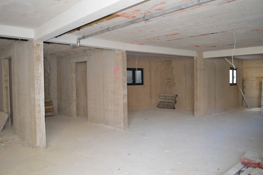 Nedokončená pivničná miestnosť s betónovými stenami a podlahami určená na parkovacie garážové státie.