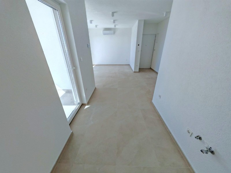 Pohľad zozadu na bytový dom s parkovacím miestom a zeleňou v Smokvici Krmpotskej