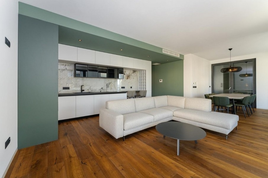 Otvorená obývačka s kuchyňou, drevená podlaha, zelená stena