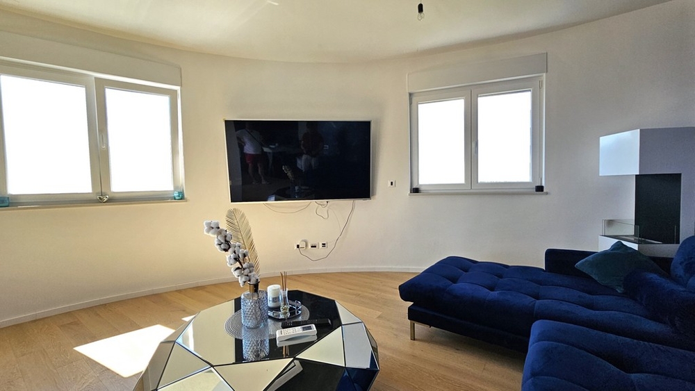 Obývacia izba s veľkými oknami a modrou pohovkou