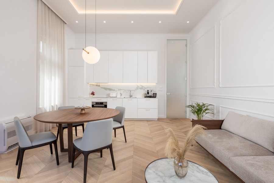 Svetlá obývacia izba s jedálenským stolom, stoličkami, kuchyňou a pohovkou