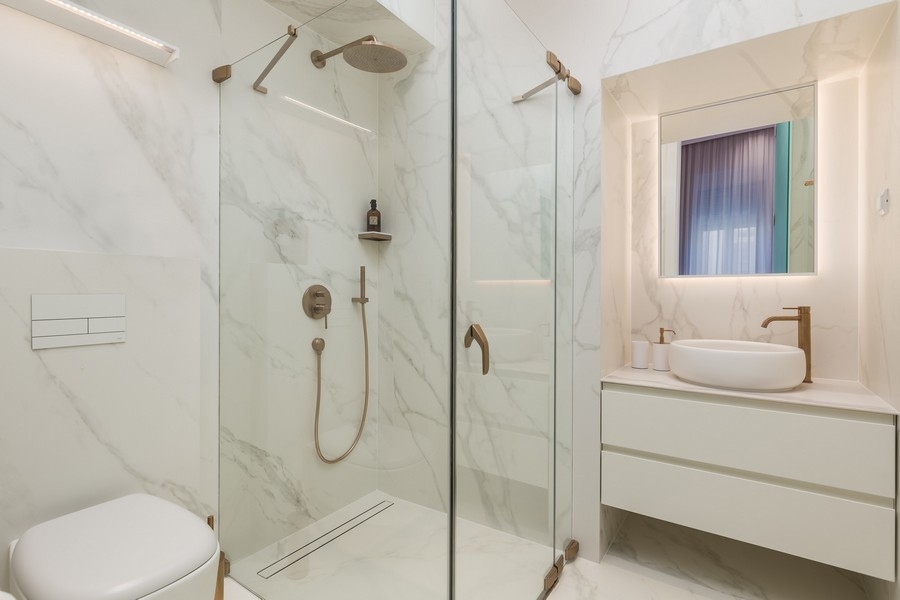 Moderná kúpeľňa so skleneným sprchovacím kútom a mramorovými obkladmi