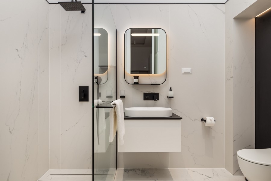 Druhá moderná kúpeľňa so skleneným sprchovacím kútom a zrkadlom