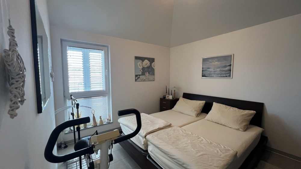 Spálňa s dvoma jednolôžkami, rotopedom a minimalistickým zariadením.