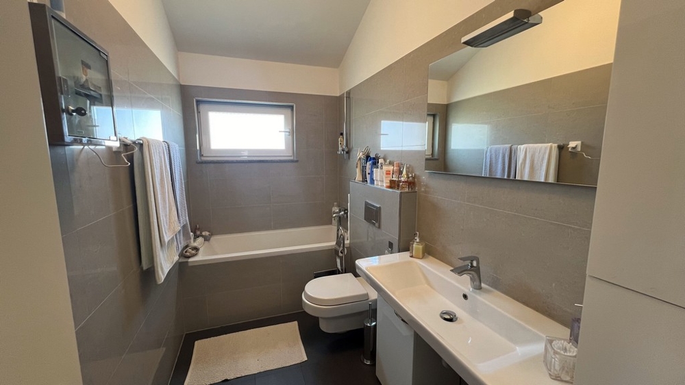 Moderná kúpeľňa s vaňou, umývadlom a WC, jednoducho a svetlo zariadená.