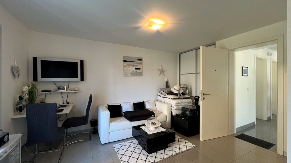 Útulný obývací priestor štúdiového apartmánu na prízemí s pohovkou, písacím stolom a TV.
