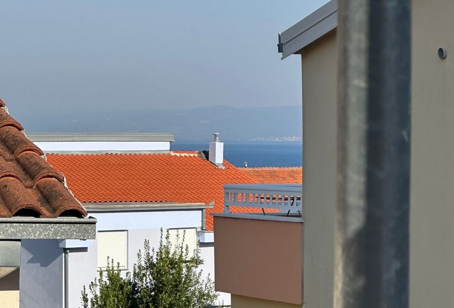 Zblízka červených škridlových striech s malým pohľadom na more v diaľke