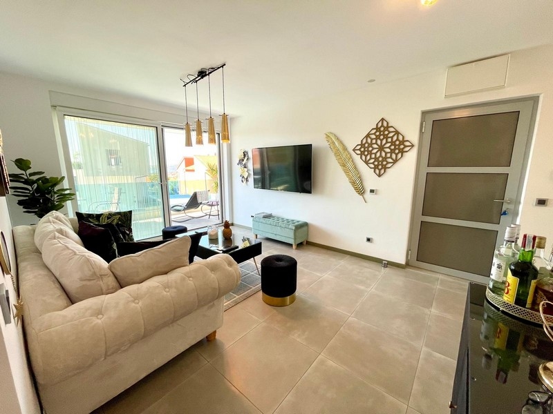 Klimatizovaná obývacia izba so svetlou pohovkou a TV.