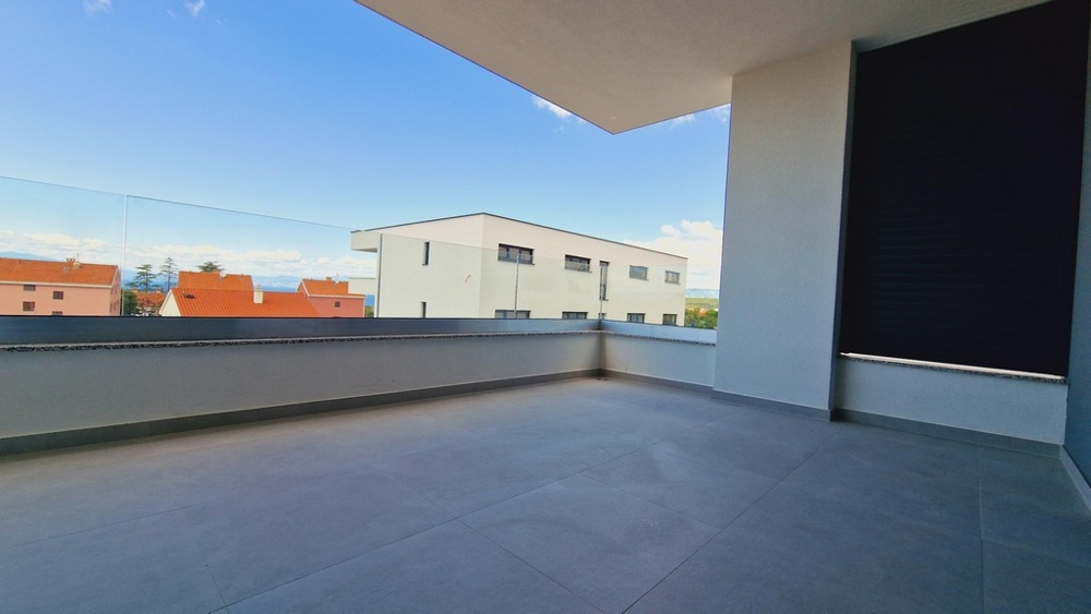 Priestranná terasa so skleneným zábradlím a výhľadom na susedné budovy a horizont