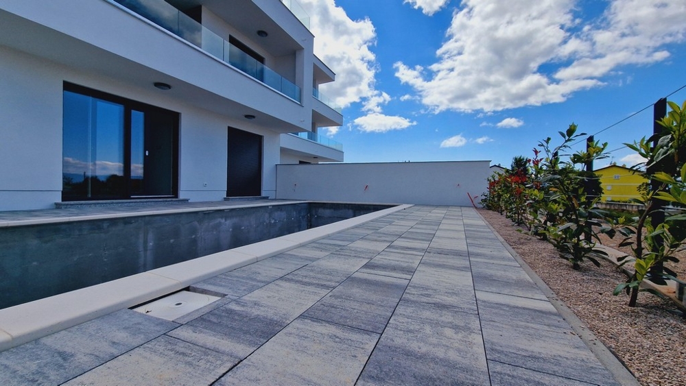 Exteriér modernej budovy s neúplným bazénom a záhradami