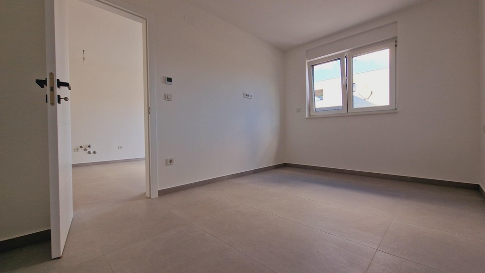 Malá svetlá izba so sivou dlažbou a oknom