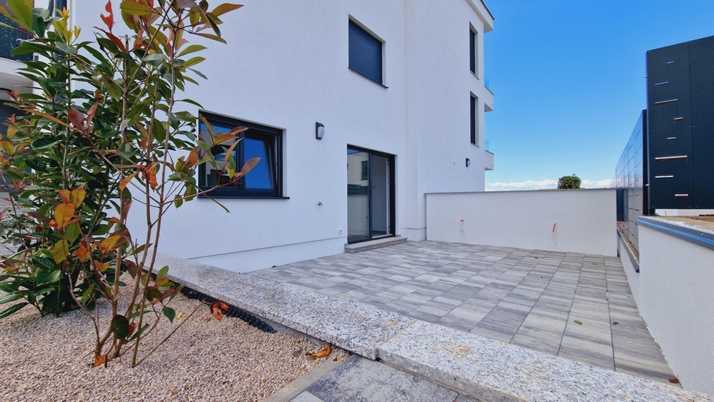 Vonkajší priestor prízemného bytu s vydláždenou terasou a rastlinami