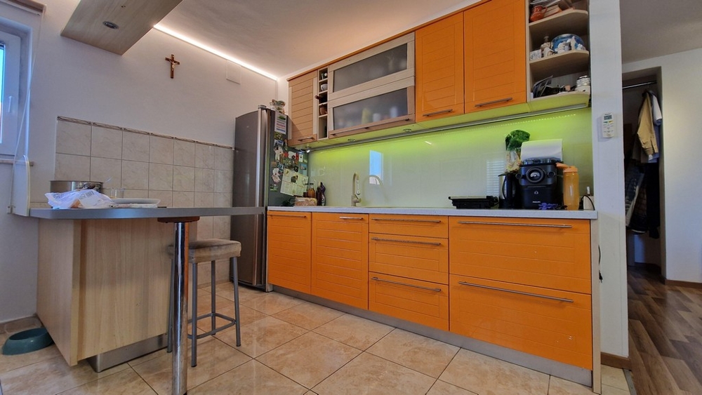 Moderná kuchyňa s oranžovými prednými časťami a jedálenským kútom