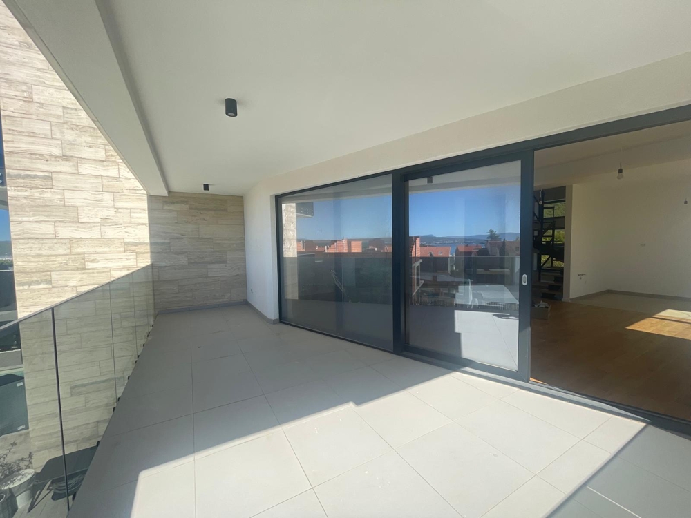 Interiér s veľkým oknom a presklenými dverami, výhľad na terasu a more, izba v nedokončenom stave